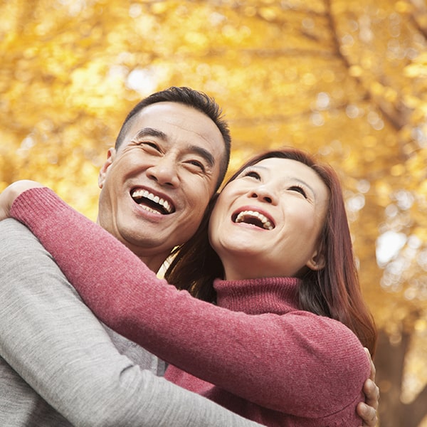 A mature couple in a park hugging while smiling